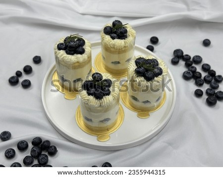 Blueberry shortcake on a wooden plate. Very shallow depth of field. Fresh Blueberry  topping with cream and yellow flower. Bakery picture free space for text.