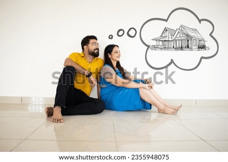 Young Indian Couple Sitting On Floor Thinking Of Getting Their Own House. Real Estate Concept. Royalty-Free Stock Photo #2355948075