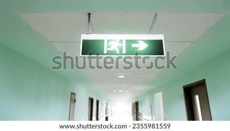 Exit sign suspended from the ceiling of hospital corridor