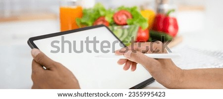 close up hand holding pen pointing tablet mockup white screen on vegetarian healthy food vegetable background. Online grocery shopping delivery app ads concept, cook book diet plan nutrition recipes.