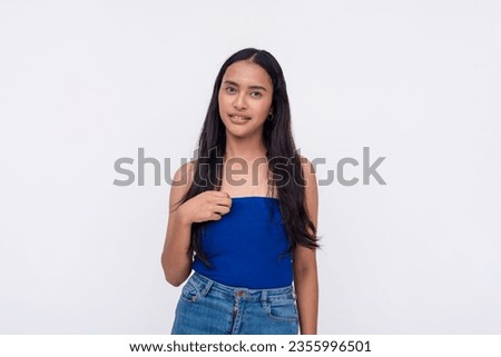 A young asian woman caught aback loses a bit of composure. A shy lady pointing to herself looking slightly unnerved. Isolated on a white background. Royalty-Free Stock Photo #2355996501