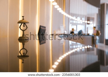 Antique silver front desk call bell on reception counter. Modern luxury hotel desk in pastel beige color background. Royalty-Free Stock Photo #2356001303