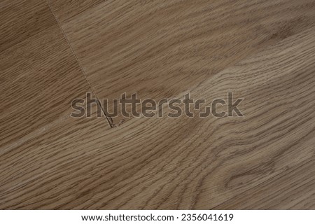 Laminate flooring with visible defects like chips, cracks, and unevenness. Royalty-Free Stock Photo #2356041619
