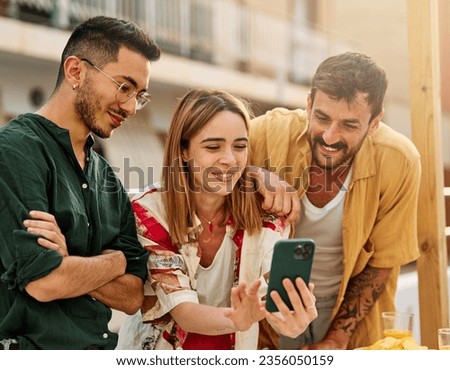 Happy young people having fun and making a selfie with a smartphone during a rooftop party during a summer holiday, standing on the rooftop terrace talking, eating and drinking, love, romance