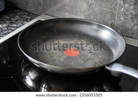 Large dirty Teflon pan in black and silver color for cooking and frying. On the black induction stove in the kitchen Royalty-Free Stock Photo #2356055505