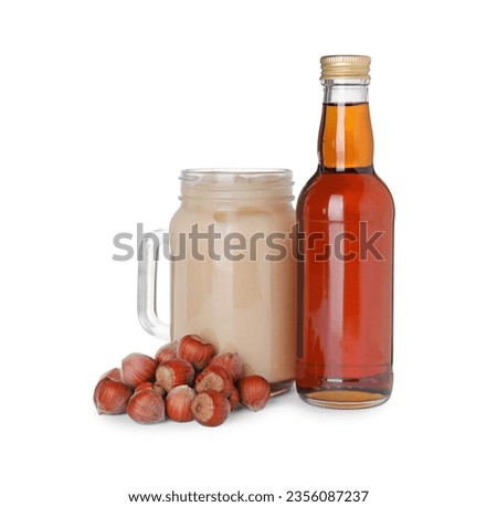 Mason jar of delicious iced coffee, syrup and hazelnuts isolated on white