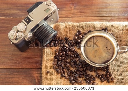 A cup of coffee with vintage camera on wood table