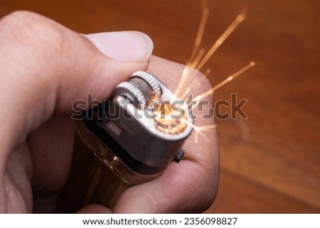 Ignited cigarette lighter against wooden background