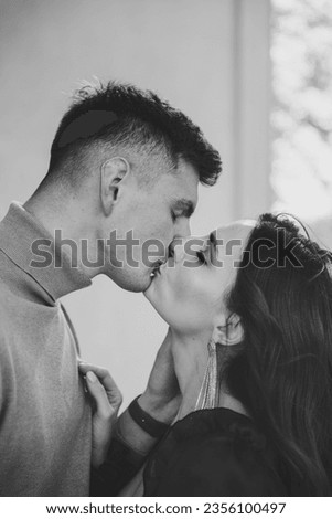 Couple kiss closeup. Man kisses woman on nature. Newlyweds walk near church outdoors. Bride and groom kissing near large columns of ancient temple at sunset. Black and white photo.