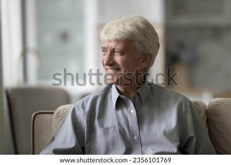 Happy thoughtful elder senior man thinking over retirement plans, good news, success, looking at window away, dreaming, enjoying leisure , relaxation on couch, smiling, laughing