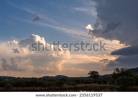 Cumulus clouds above a dark plain at sunset