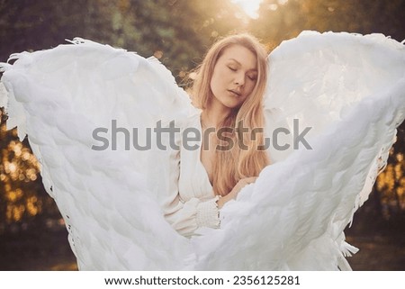 Beautiful girl dressed as an angel in the evening garden Royalty-Free Stock Photo #2356125281