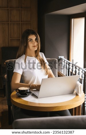 Woman specialist targetologist works at a laptop in a coffee shop. Concept of marketing and targeting