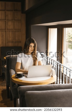 Woman specialist targetologist works at a laptop in a coffee shop. Concept of marketing and targeting