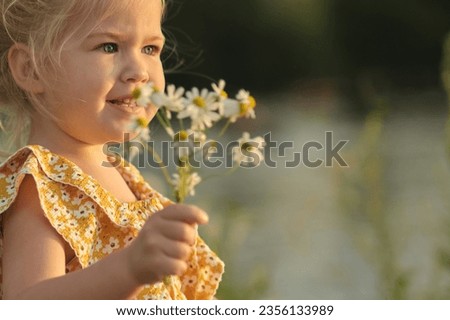 Holding a bunch of daisies, little girl smiles amidst backdrop of natural beauty, symbolizing next generation's role in environmental stewardship. importance of educating youth about sustainability. Royalty-Free Stock Photo #2356133989