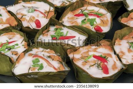 a photography of a plate of food with rice and vegetables, burritos wrapped in banana leaves with a sauce and toppings.