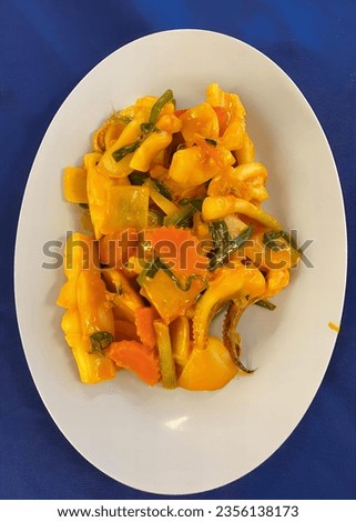 a photography of a plate of food with peppers and other vegetables, butternut squash and peppers on a white plate on a blue table.