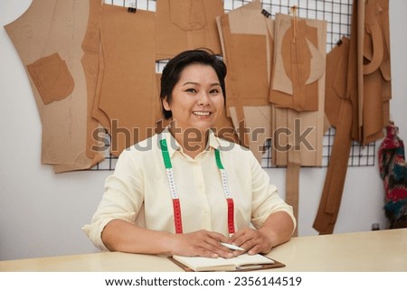 Confident Asian female fashion designer working in her studio