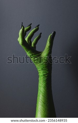 Vertical image of green monster hand with black nails with hold gesture on grey background. Halloween, tradition and celebration concept. Royalty-Free Stock Photo #2356148935