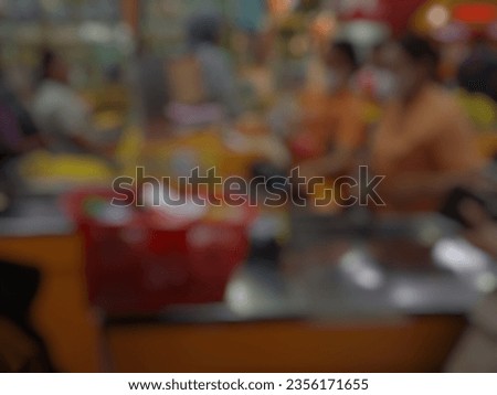 A blurry image of a woman paying for her groceries at a minimarket cashier or a Bokeh image of a typical Indonesian retail store. Defocused abstract background of indonesian retail shop.