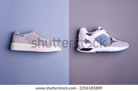 Side view of two trendy different sneakers in gray, white, and blue colors, isolated on a two-color blue-gray background. Top view, flat lay. Creative fashion photography. Summer shoe sale campaign