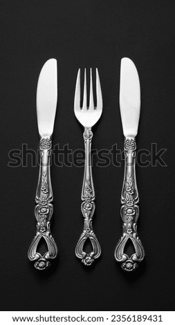 Top view of two old silver knives and one fork isolated on a black background Royalty-Free Stock Photo #2356189431