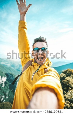 Young hiker man taking vertical selfie portrait on the top of mountain - Happy guy smiling at camera - Tourism, sport life style and social media influencer concept