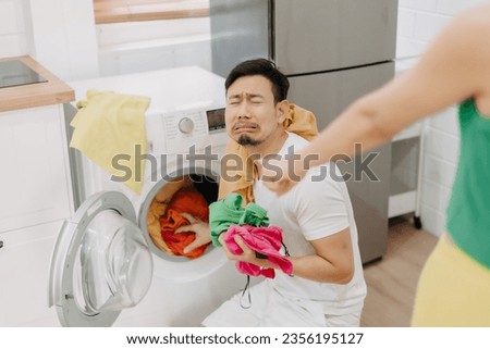 Funny asian man crying being force by his wife to wash clothes and do housework. Royalty-Free Stock Photo #2356195127
