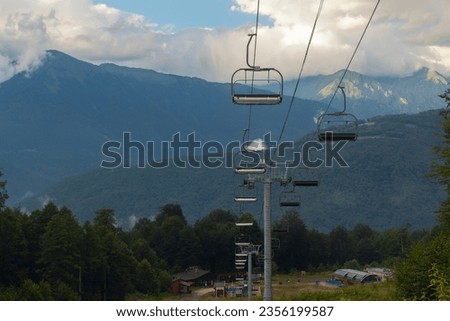 A ski resort in Sochi against the backdrop of nature on a summer day. Cable car with opened cabins against the background of mountains and cloudy sky
