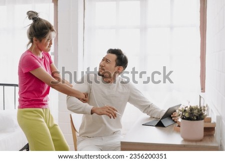 Asian wife asking husband to stop working and watching with computer tablet. Royalty-Free Stock Photo #2356200351