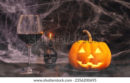 Halloween pumpkin head jack lantern on a wooden table with burning candles and human skull