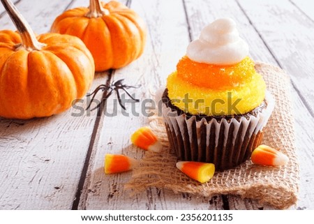 Halloween candy corn chocolate cupcake. Close up against a white wood background.