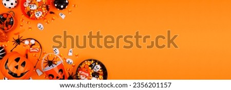 Halloween trick or treat corner border with jack o lantern pails and a variety of candy. Top down view on an orange banner background with copy space. Royalty-Free Stock Photo #2356201157