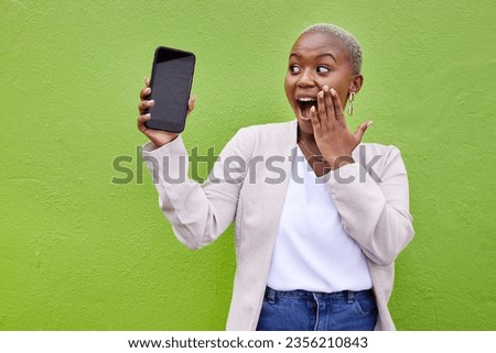 Woman, surprise and phone screen with mockup by a wall or green background with wow advertising. Shocked African person or winner with a smartphone for social media, mobile app chat or website space
