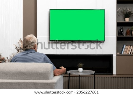 Aged man sitting on the couch and watching tv. Green screen concept	