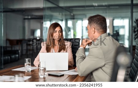Two mature professional business executives working having conversation at meeting. Board team members using laptop computer talking sitting at table discussing digital corporate strategy in office. Royalty-Free Stock Photo #2356241955
