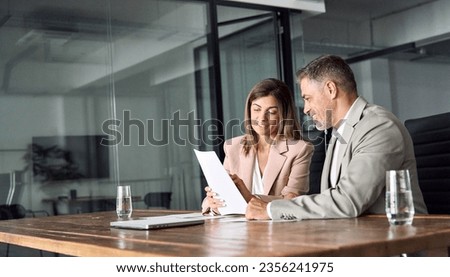 Two professional executives discussing financial accounting papers working with paperwork in office. Mature business woman and man managers holding legal corporate documents at meeting. Copy space. Royalty-Free Stock Photo #2356241975