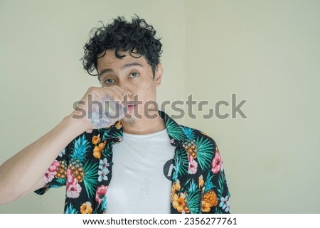 Young curly man feel tired and thirsty then drink the mineral water. man's beachwear. The photo is suitable to use for man expression advertising, fashion life style and healthy life style.