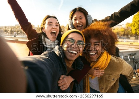 Selfie of multi-ethnic cheerful friends enjoying sunny winter day outdoors. Group of people looking at camera smiling.