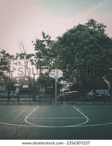A basketball hoop in the park in the evening.
