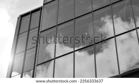 Glass modern building with blue sky background. View and architecture details. Urban abstract - windows of glass office building in  sunlight day. Black and white.