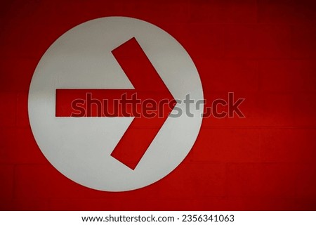 Arrow sign in white circle on red brick wall background, Directional Arrow  pointing to right side