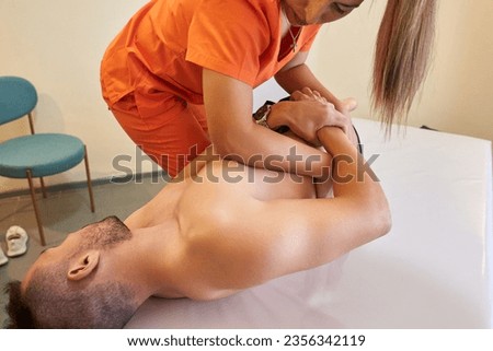Female doctor readjusting a male patient's lumbar spine Royalty-Free Stock Photo #2356342119