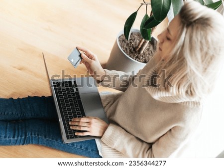 Young woman holding credit card and using laptop computer. Girl working online. Online shopping,  internet banking,  working from home 