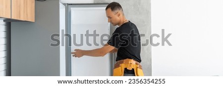 Young Male Technician Checking Fridge With Digital Multimeter