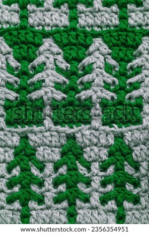 Green grey crochet Christmas tree ornament close up. Christmas knitted background.