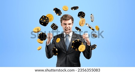Happy businessman with arms raised, looking at the camera. Falling dollar coins and dice with poker chips on blue background. Concept of big win, luck and gambling