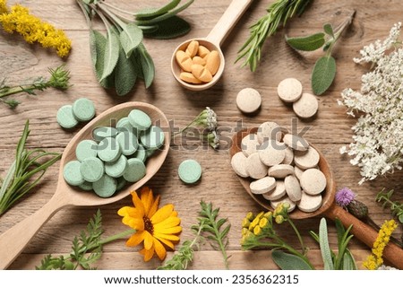 Different pills, herbs and flowers on wooden table, flat lay. Dietary supplements Royalty-Free Stock Photo #2356362315