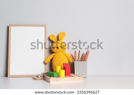 Empty square frame, stationery and different toys on white table, space for text