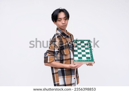 A nerdy young asian man holding a chess board. Isolated on a white background.